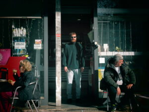 L'immagine rappresenta il cantante in uno scenario quotidiano, sull'uscio di un bar.